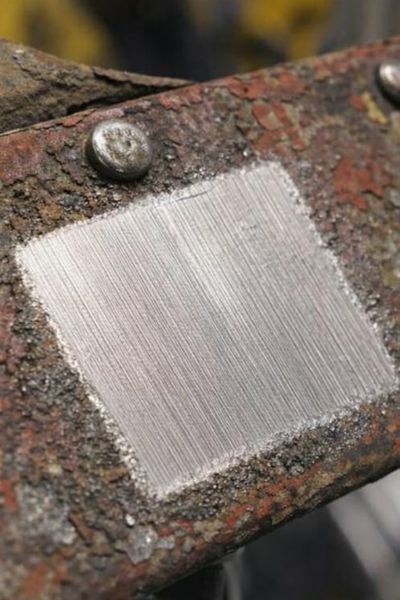 Pièce en fer après décapage laser, une zone carrée de métal propre apparaît nettement sur la surface oxydée