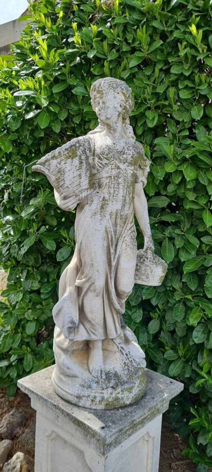 La même statue de jardin en pierre couverte de mousse et de lichen avant nettoyage